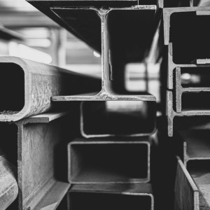 Gestapelte Stahlprofile in verschiedenen Formen und Querschnitten, darunter Rechteckrohre, H- und U-Träger im Lager von Rewesta Metallbau.