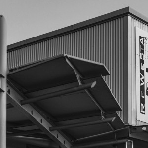 Architektonisches Detail des Eingangsbereichs von Rewesta Metallbau mit Lochblechträgern und großem Firmenschild an der Fassade.