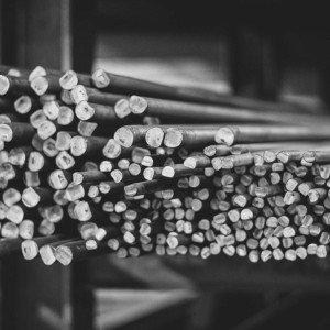 Nahaufnahme eines Bündels blanker Metallstäbe in rundem und eckigem Querschnitt, gestapelt im Lager von Rewesta Metallbau.